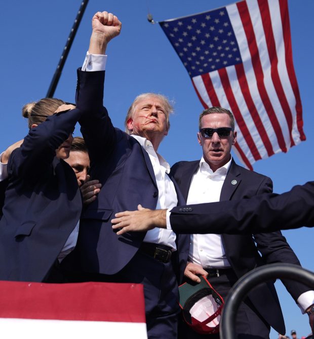 Republican presidential candidate former President Donald Trump gestures as he is surrounded by U.S. Secret Service agents as he leaves the stage at a campaign rally, Saturday, July 13, 2024, in Butler, Pa. (Evan Vucci/AP)