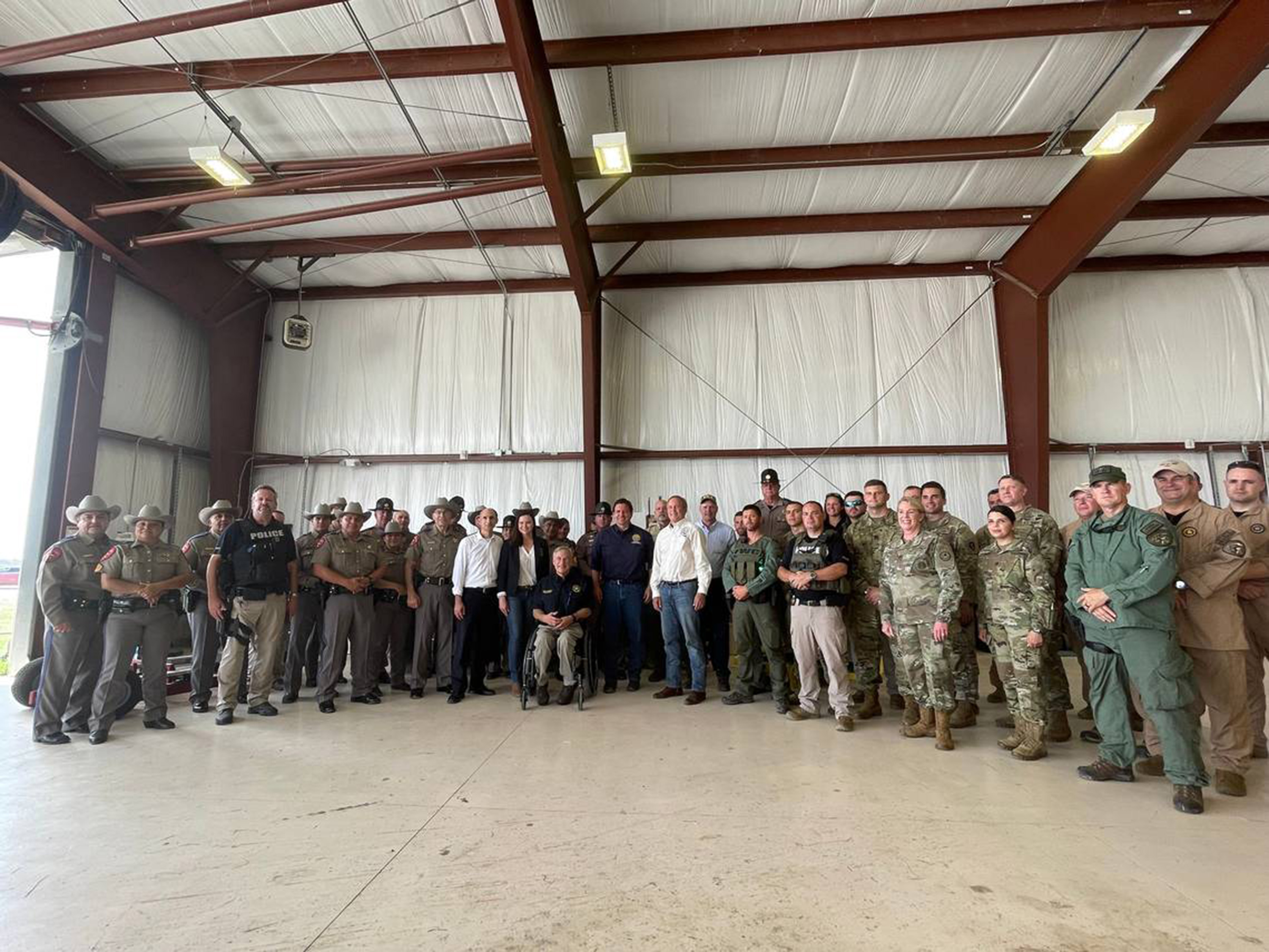 El gobernador de Florida, Ron DeSantis, y el gobernador de Texas, Greg Abbott, se toman una foto con los funcionarios encargados de hacer cumplir la ley que participaron en la misión. El gobernador de Florida, Ron DeSantis, y el gobernador de Texas, Greg Abbott, se toman una foto con los funcionarios encargados de hacer cumplir la ley que participaron en la misión.