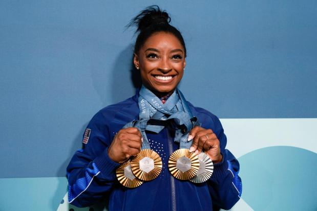 Simone Biles, of the United States, holds up her medals after the women's artistic gymnastics individual apparatus finals Bercy Arena at the 2024 Summer Olympics, Monday, Aug. 5, 2024, in Paris, France. (AP Photo/Charlie Riedel)
