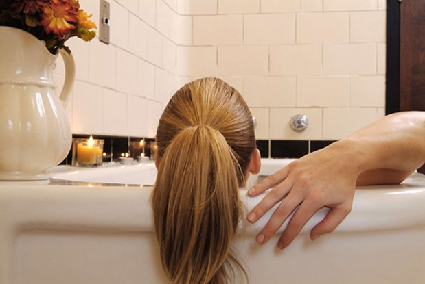 The back of a woman's head against the edge of a bathtub